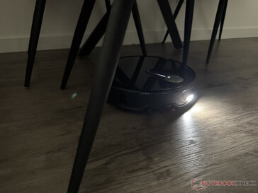 De Roborock Qrevo Slim met het licht aan in het stoelpootdoolhof